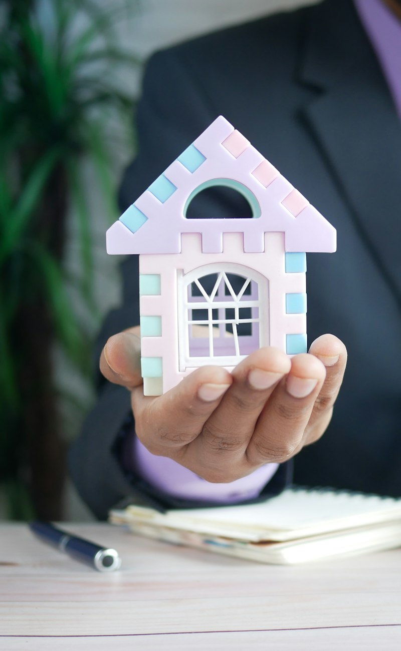 Advisor holding a small house model next to a calculator